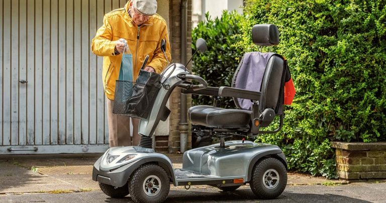 Scooter eléctrico Salvatec junto a persona mayor dejando una bolsa